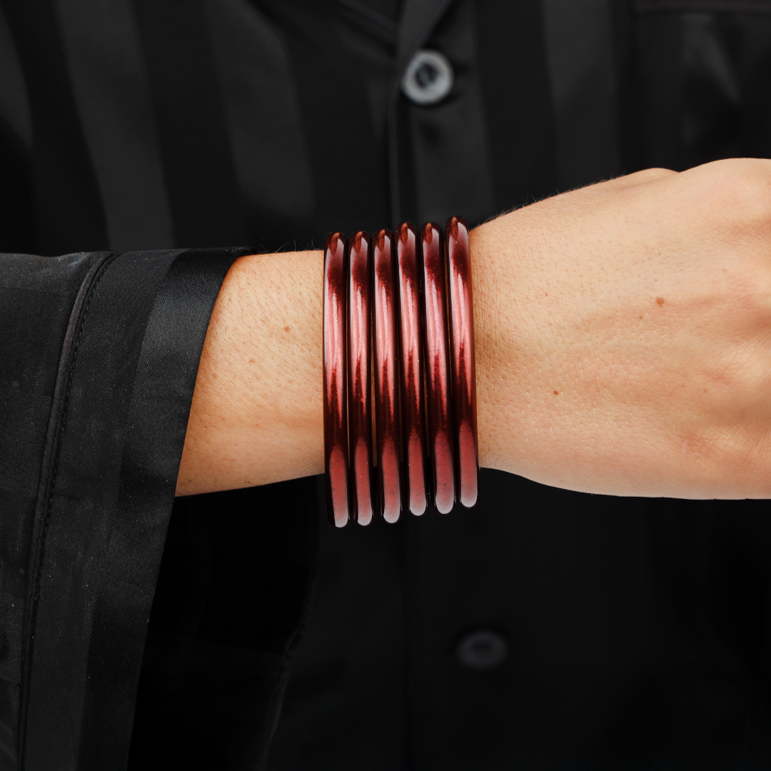 Red bangles on a person's wrist with a black background