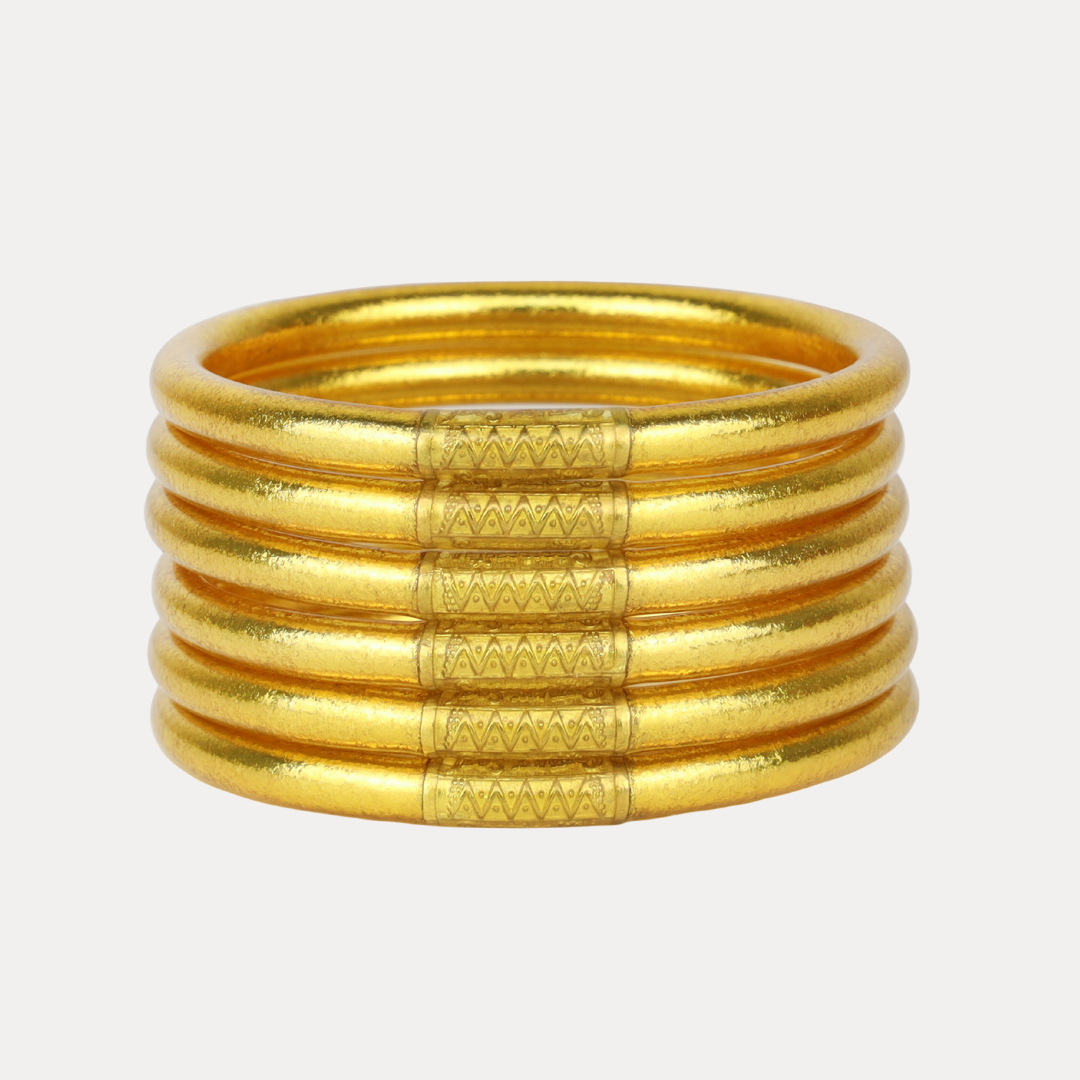 Stack of gold bangles on a light beige background